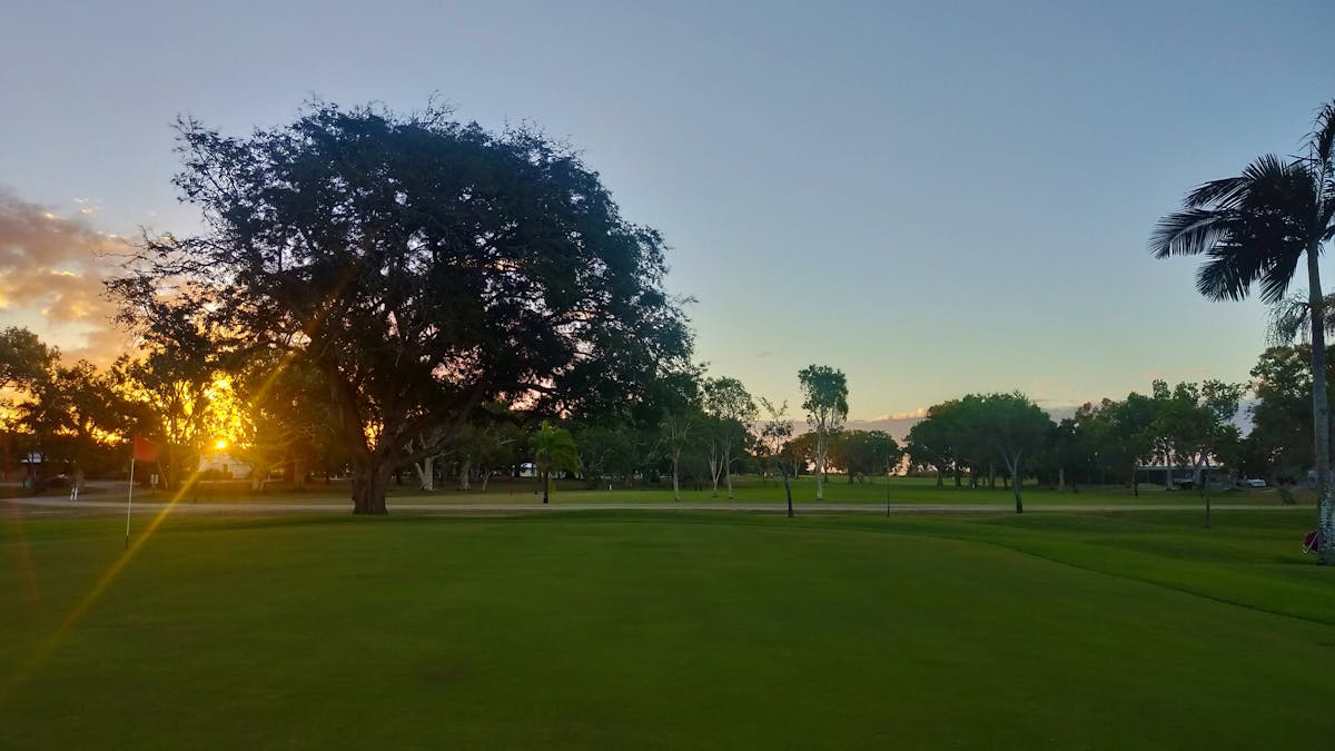 Sun is rising in the background of a green golf course
