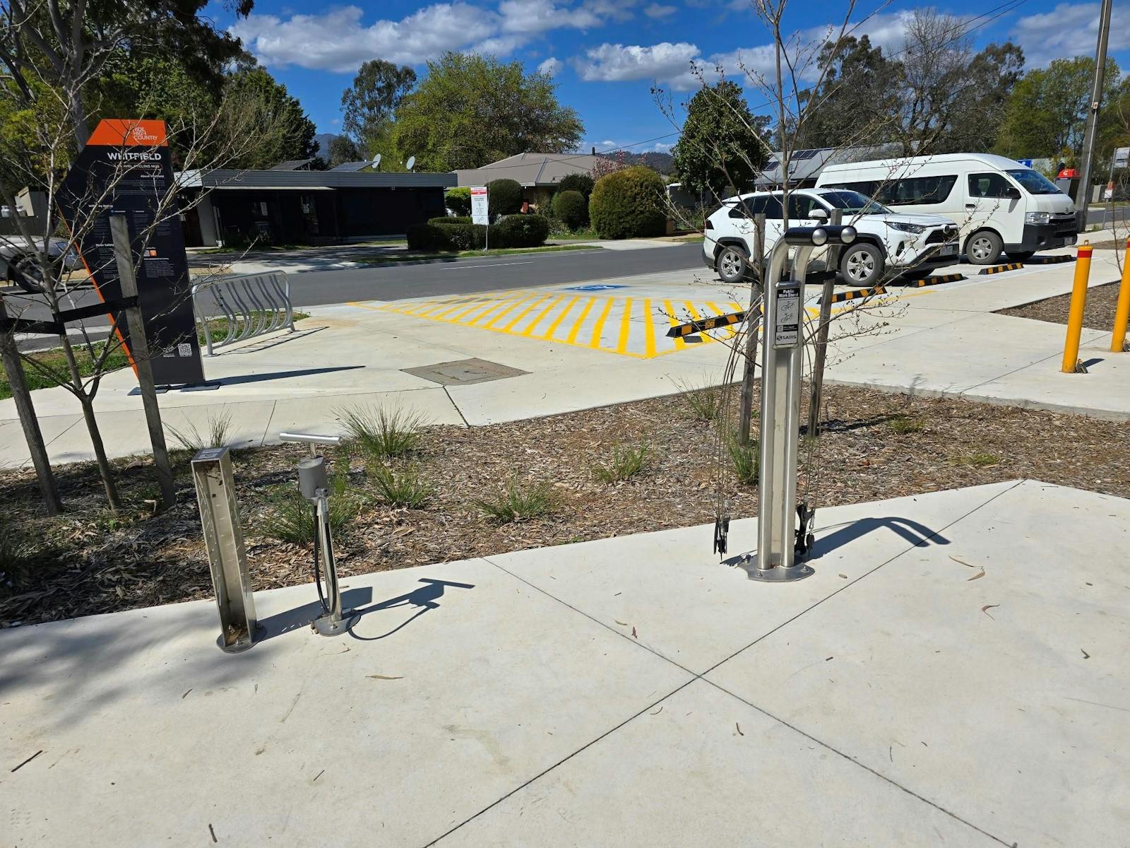 Bike repair equipment on a concrete pad in front of an accessible carpark space