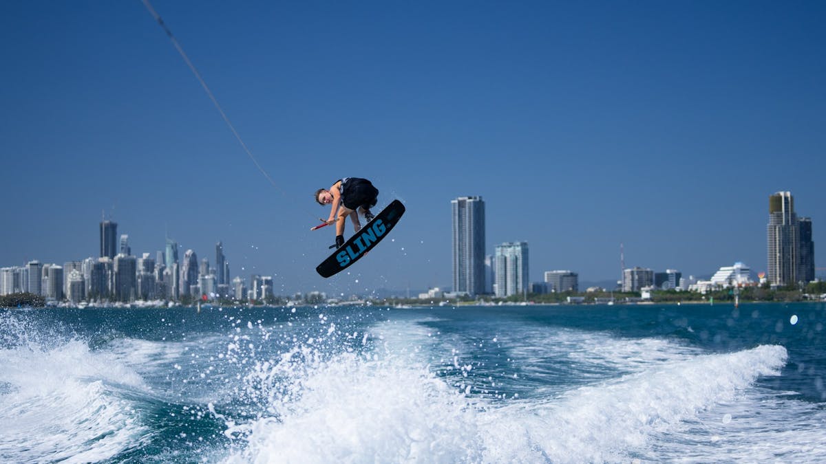 Wake boarder doing massive air grab of the board.
