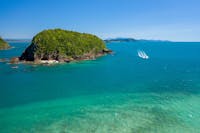 A boat cruises across tropical seas next to an island