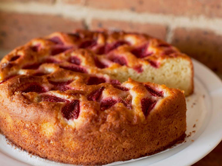 Strawberry and almond whole cake, ready to be sliced and served with cream