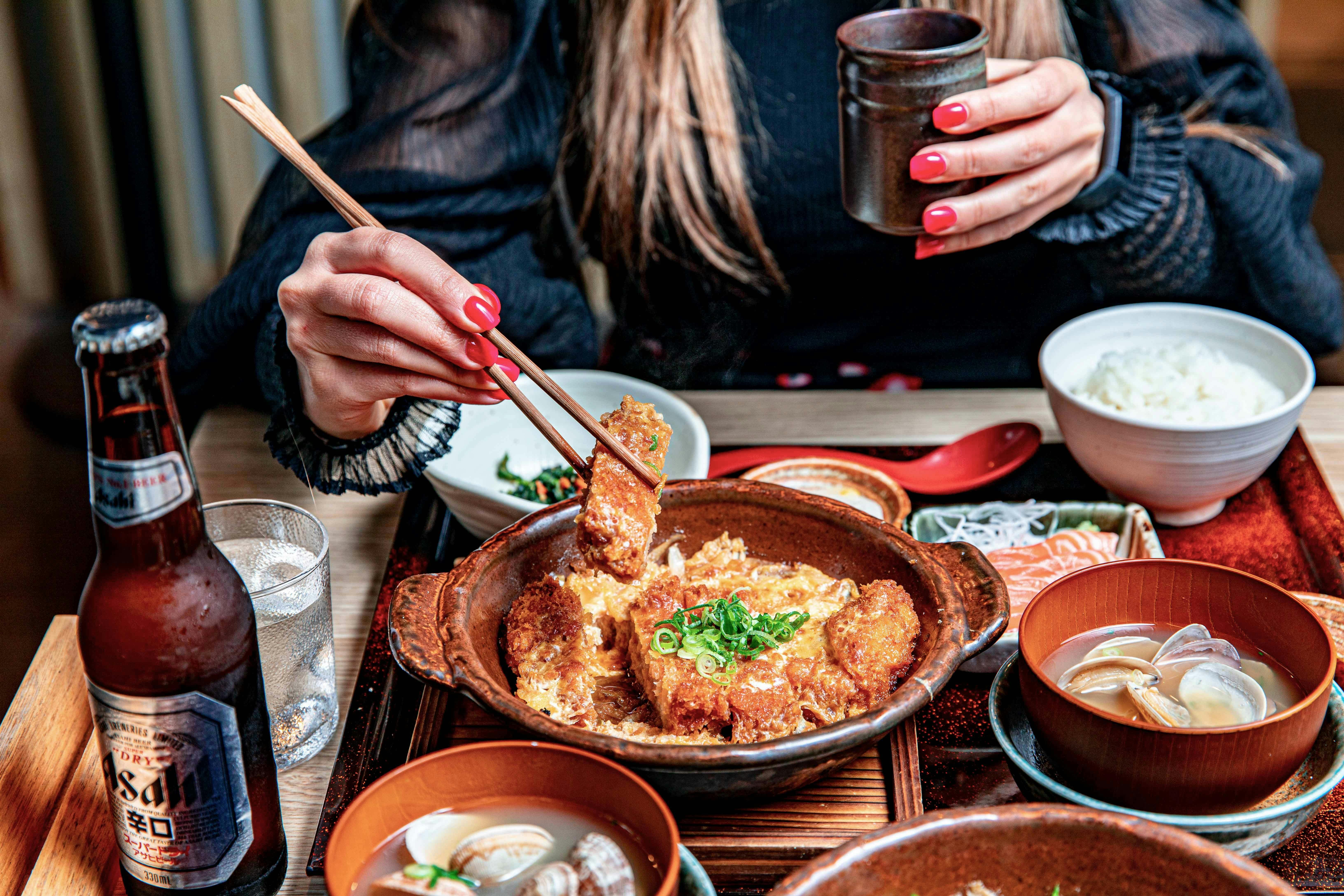 Foto einer Frau, die japanisches Essen mit Stäbchen isst