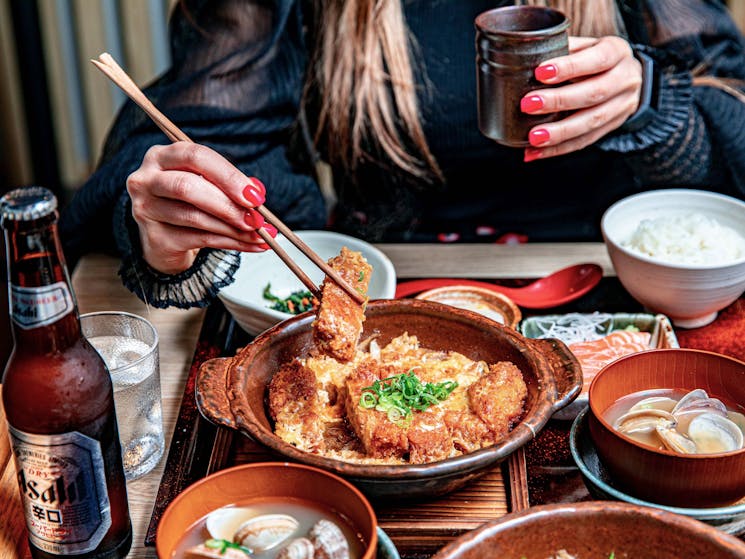 Photo of woman eating Japanese meal with chopsticks