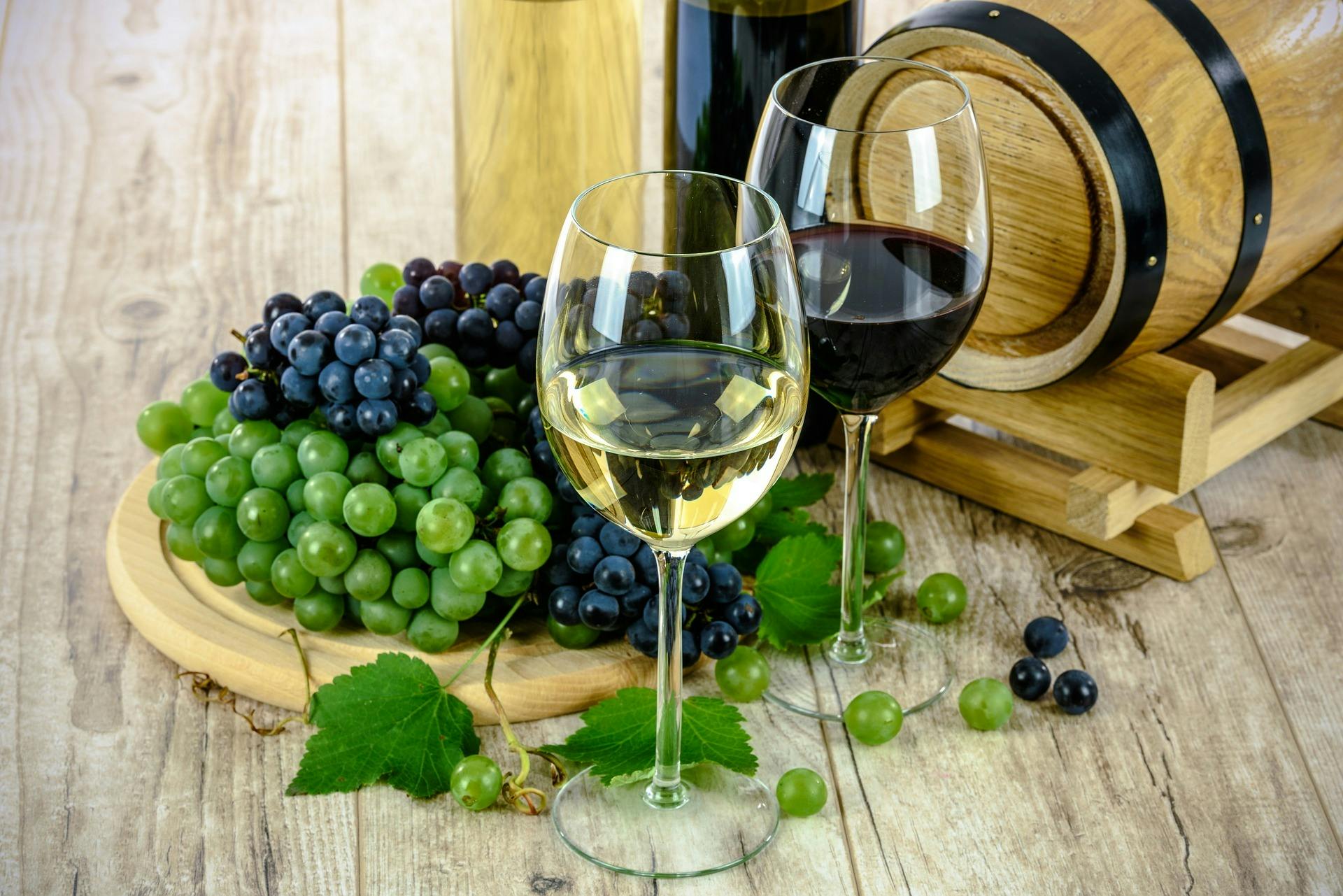 White wine with grapes and wine barrel