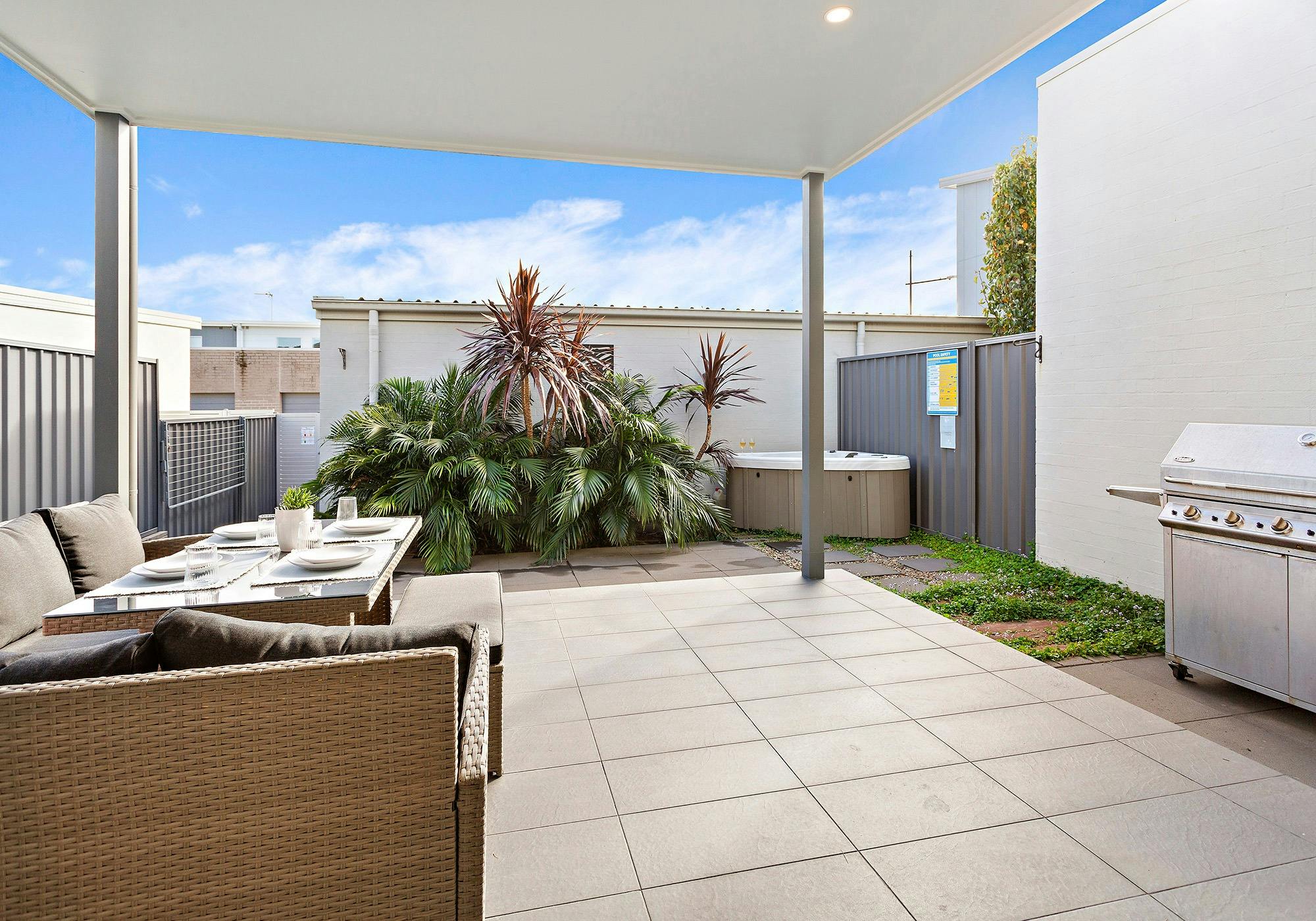 Covered alfresco area with table, lounge chairs, barbecue and spa.