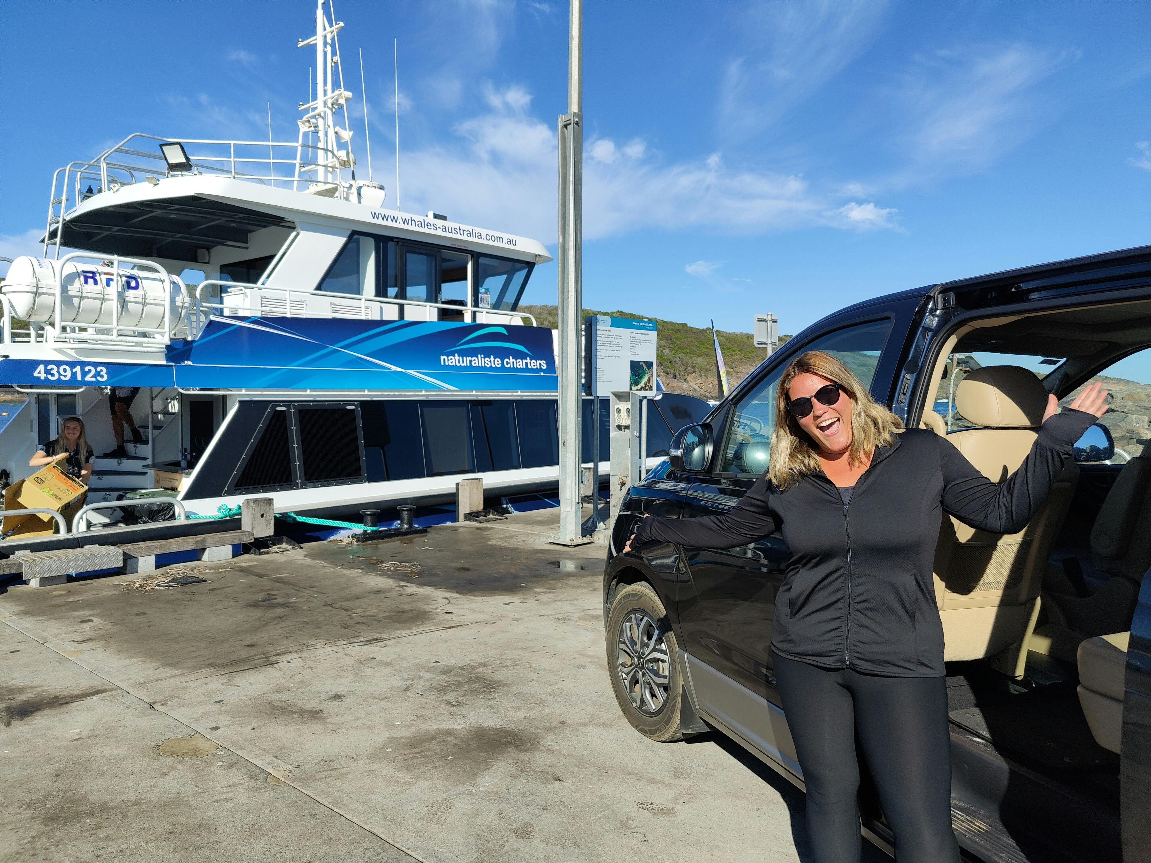 woman waving in front of vehicle in front of boat at jetty