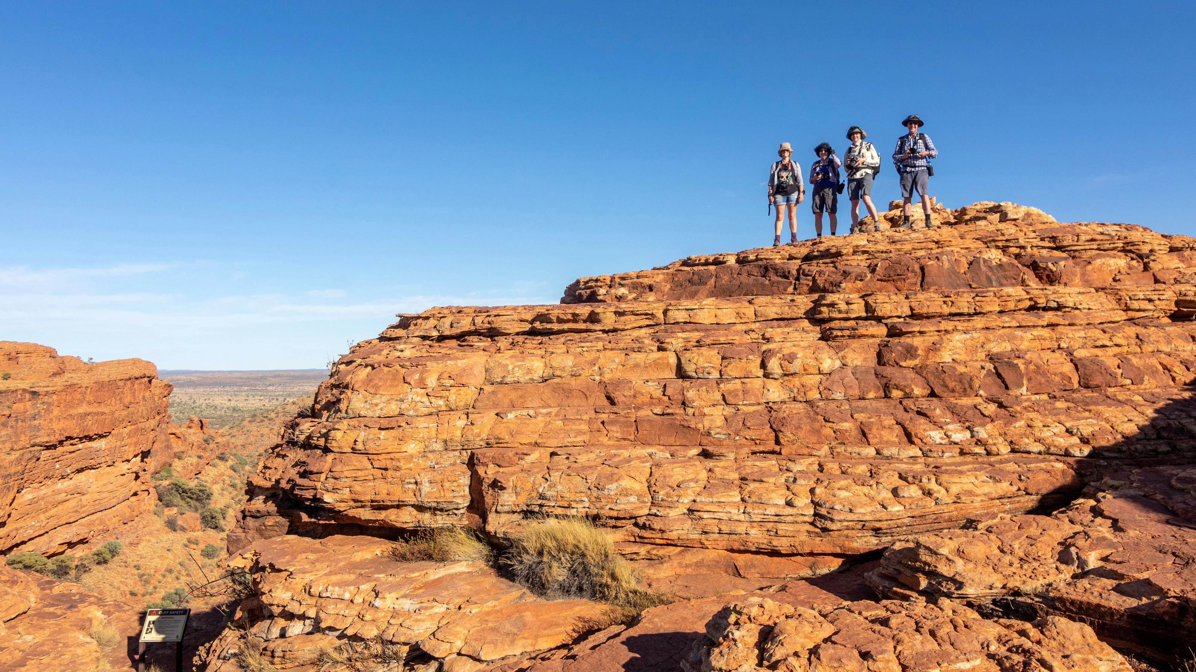 4 tour guests standing on some rocks with a canyon behind them