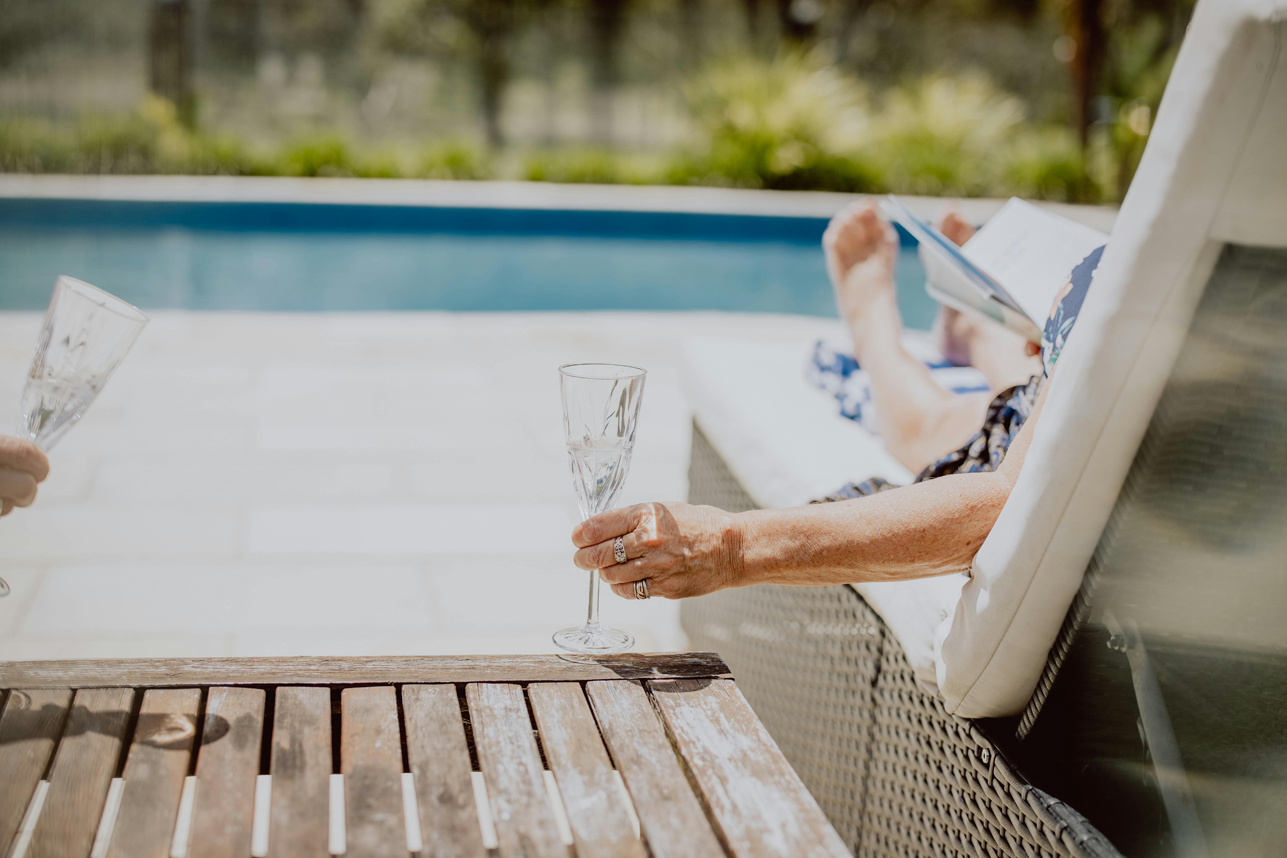 Woman holding a glass laying by a pool