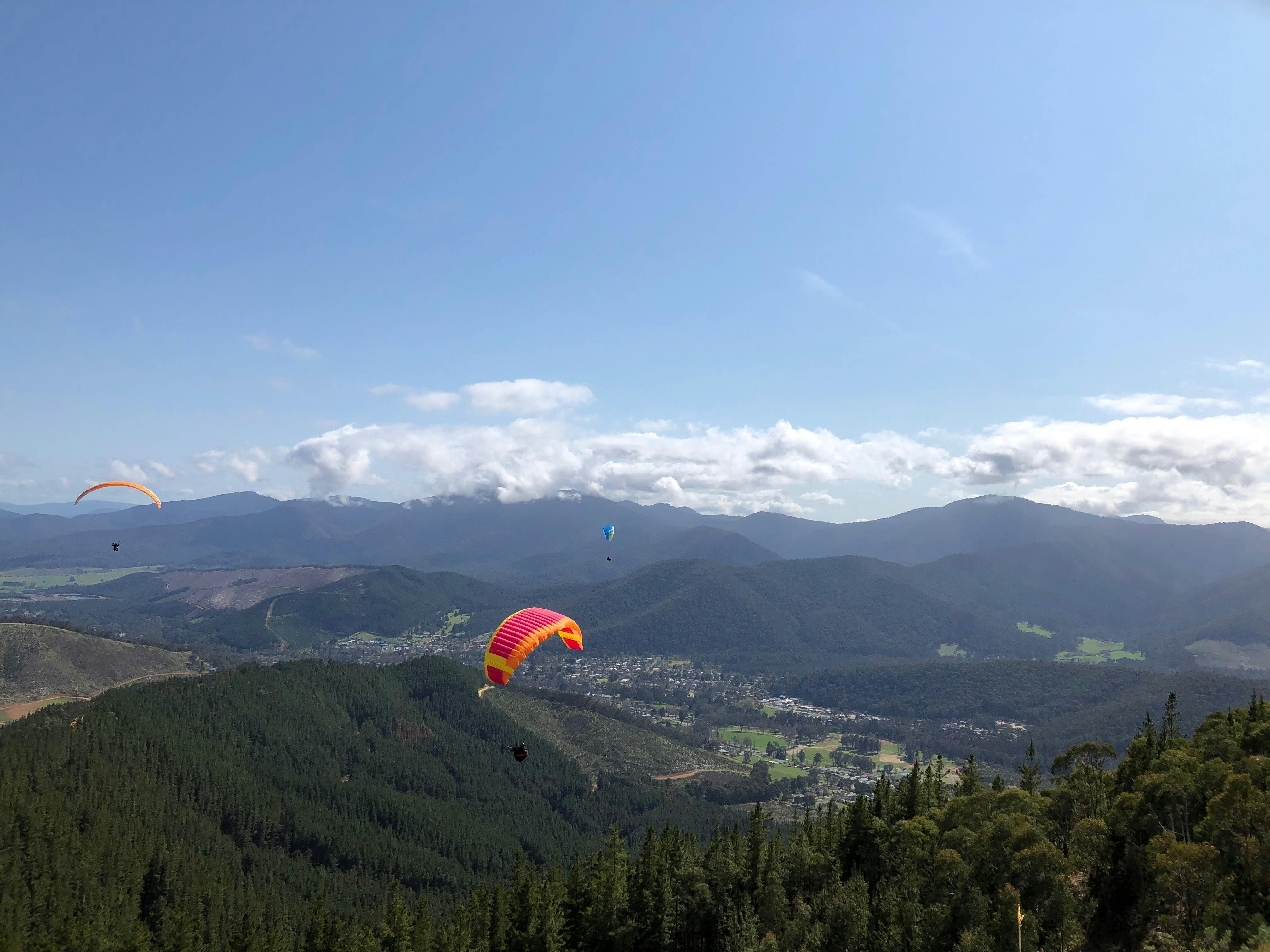 Multiple gliders are above Bright and its mountains