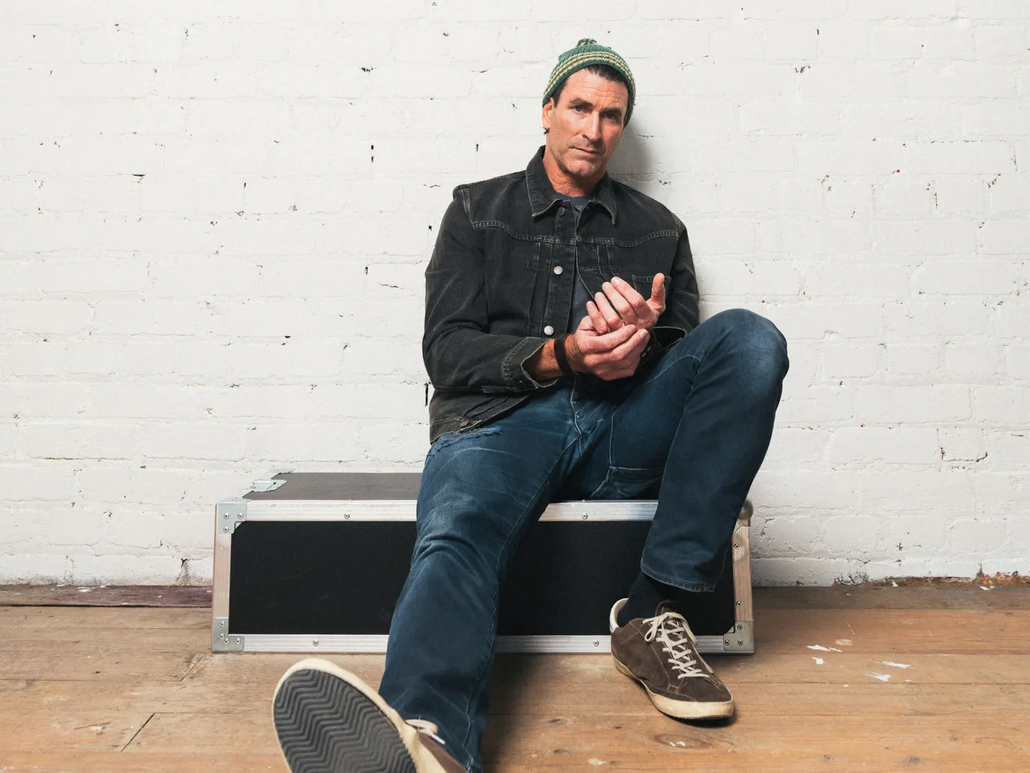 A press shot of Pete Murray against a white brick wall