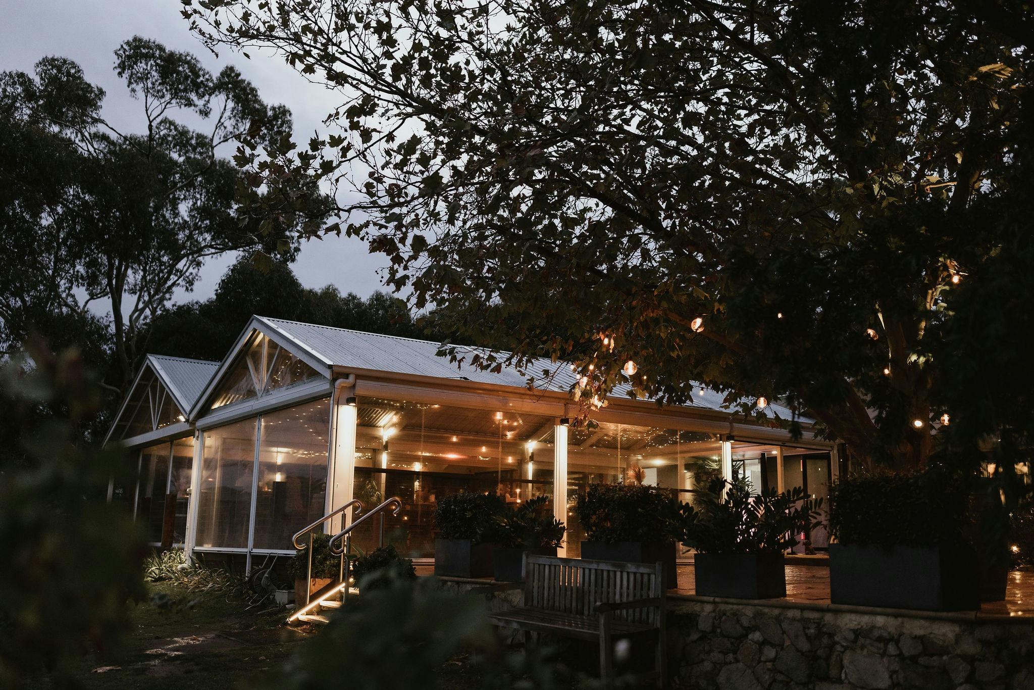 A night time view of a cellar door with fairy lights surrounded by trees.