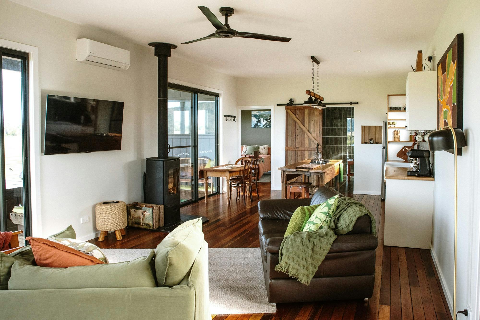 Photo of living room space with lounges, wood burning fire and kitchen
