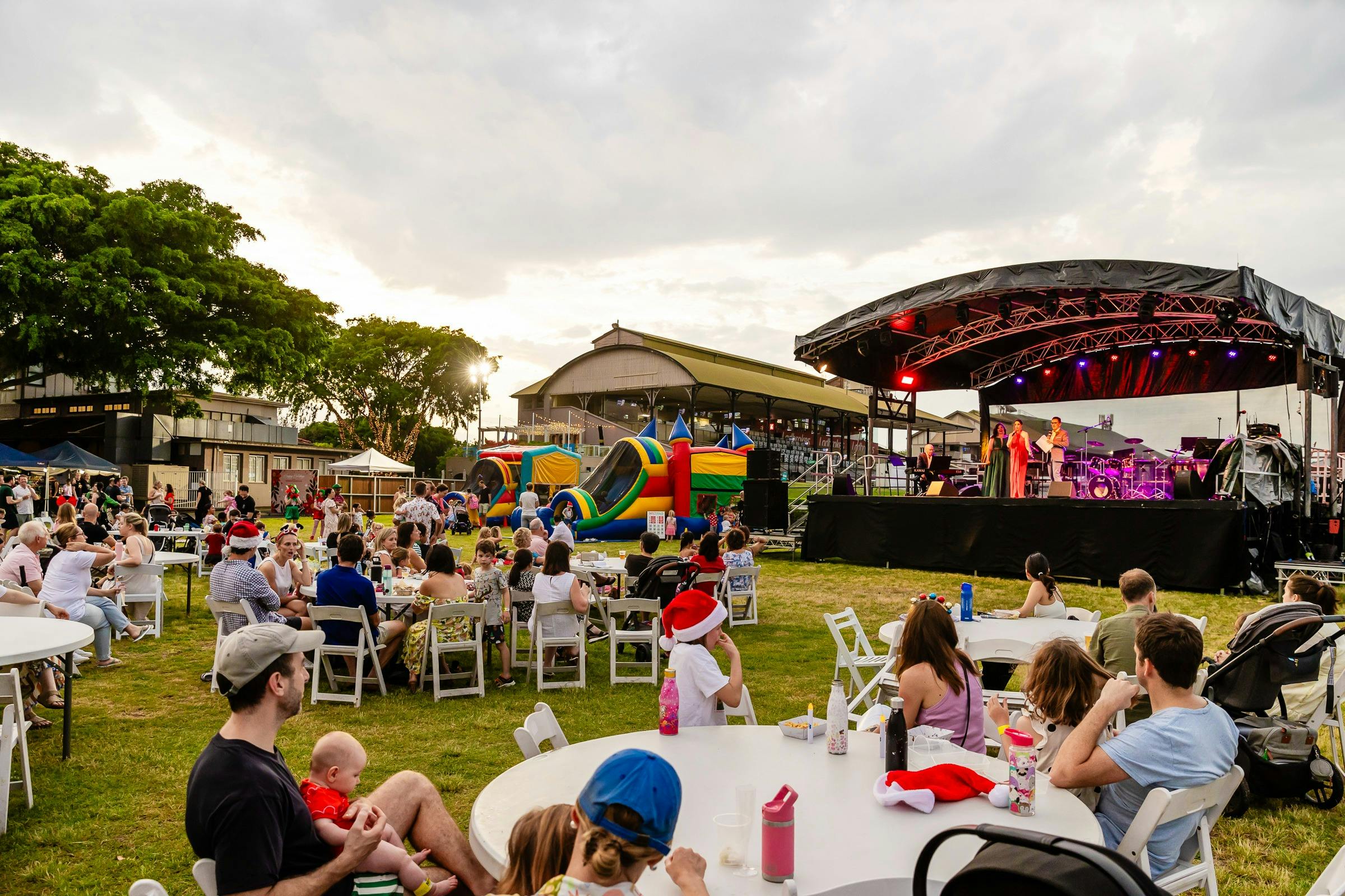 A Christmas carols event takes place, families are seated at tables in front of the main stage.