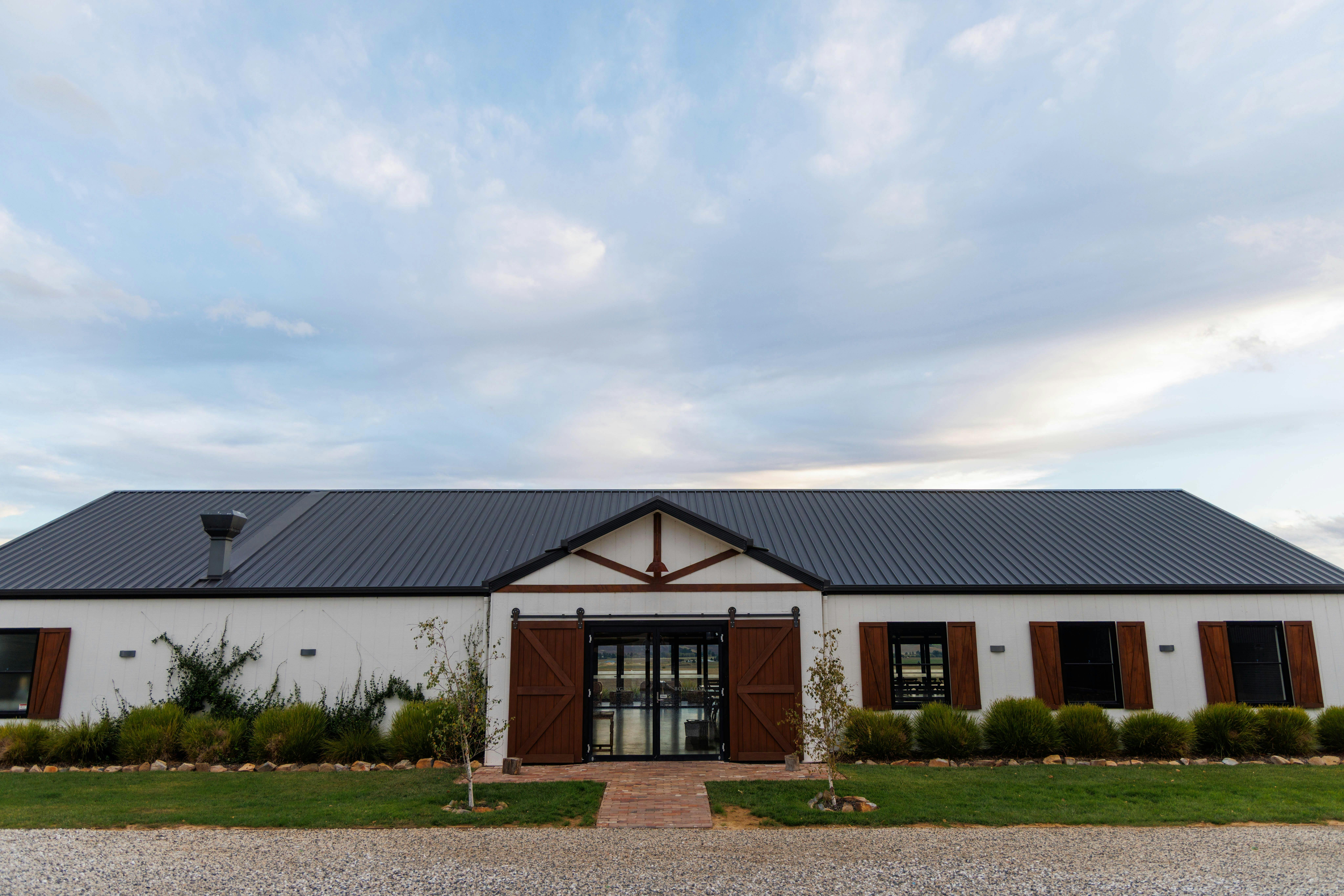 A white barn-like function centre with a premium-rural white exterior with dark and timber accents
