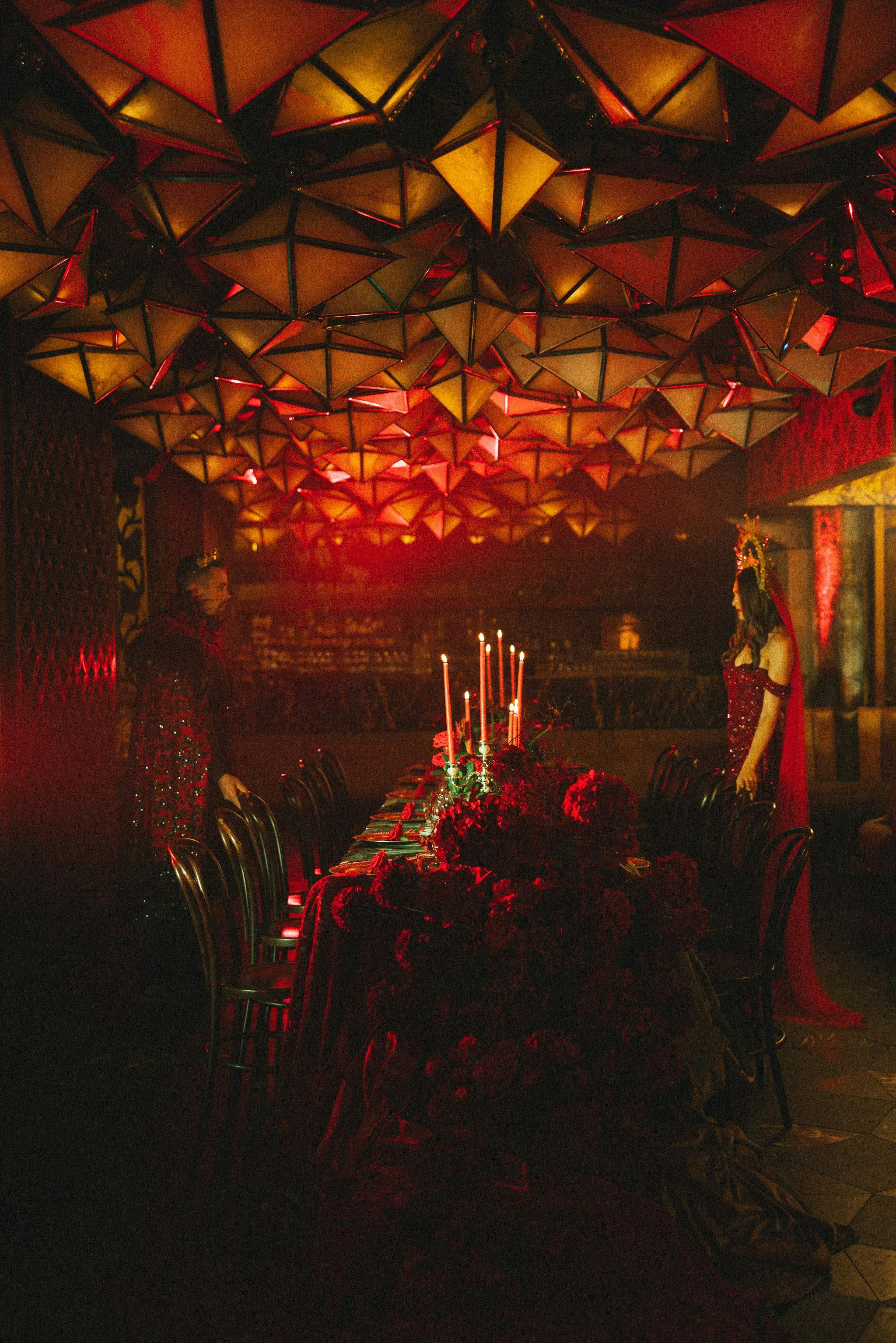 An elaborate banquet table set with red flowers, place settings and candles