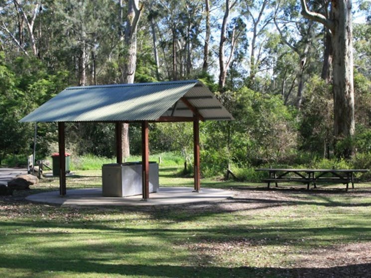 A barbecue shelter with picnic tables nearby at Carter Creek picnic area in Lane Cove National Park.