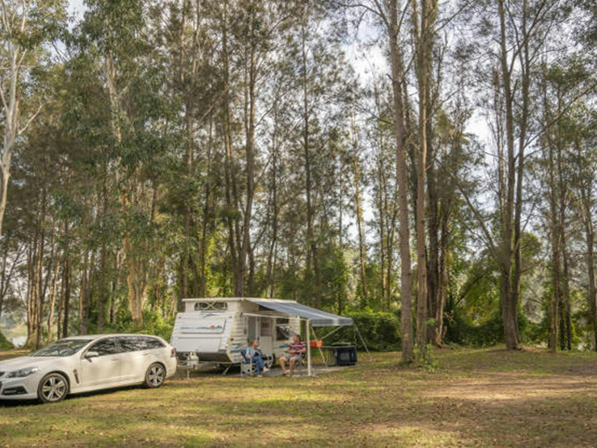 Ein Paar sitzt vor seinem Wohnwagen auf dem Campingplatz Cattai im Cattai-Nationalpark an der Hawkesbury-Halbinsel.