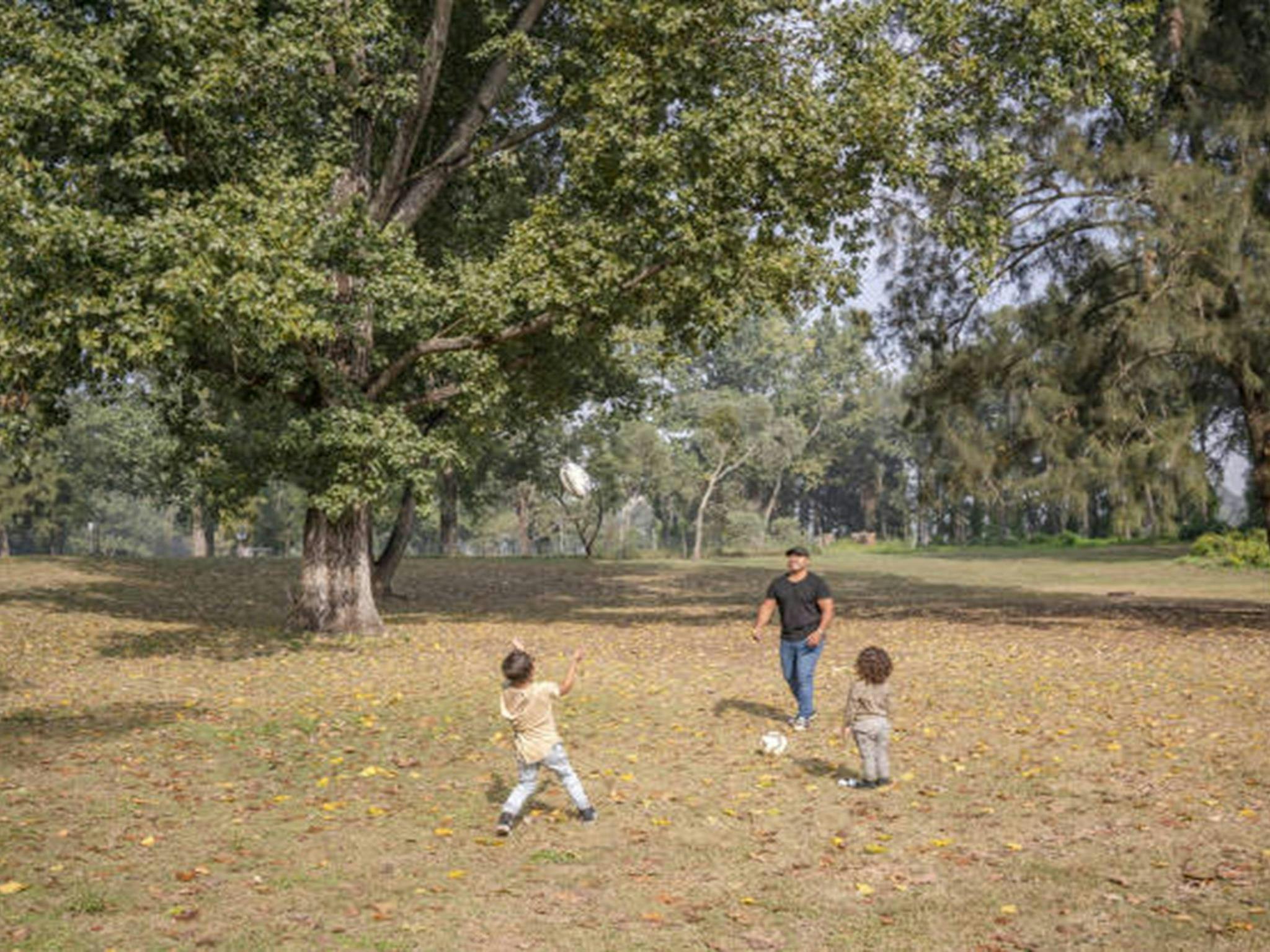 Ein Mann spielt mit zwei Kindern Ballspiele auf dem Campingplatz Cattai im Cattai-Nationalpark.
