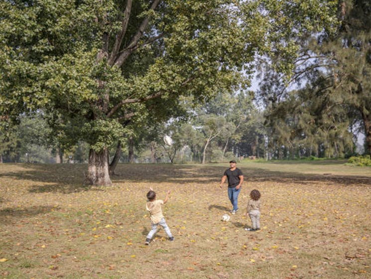 A man playing ball games with two children at Cattai campground in Cattai National Park, on the