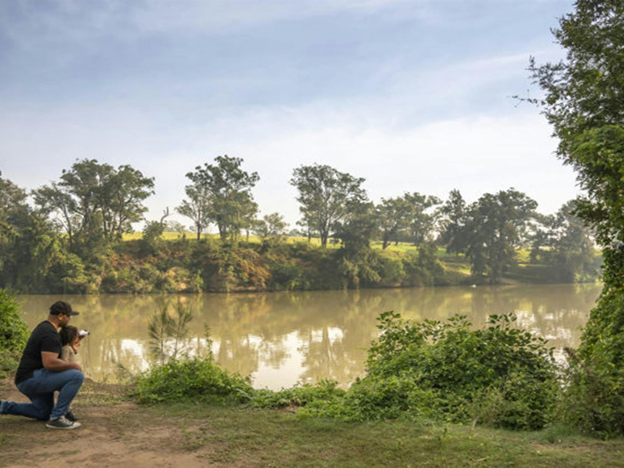 Ein Vater hilft seiner Tochter, mit einem Fernglas Wildtiere am Hawkesbury River bei Cattai zu beobachten.
