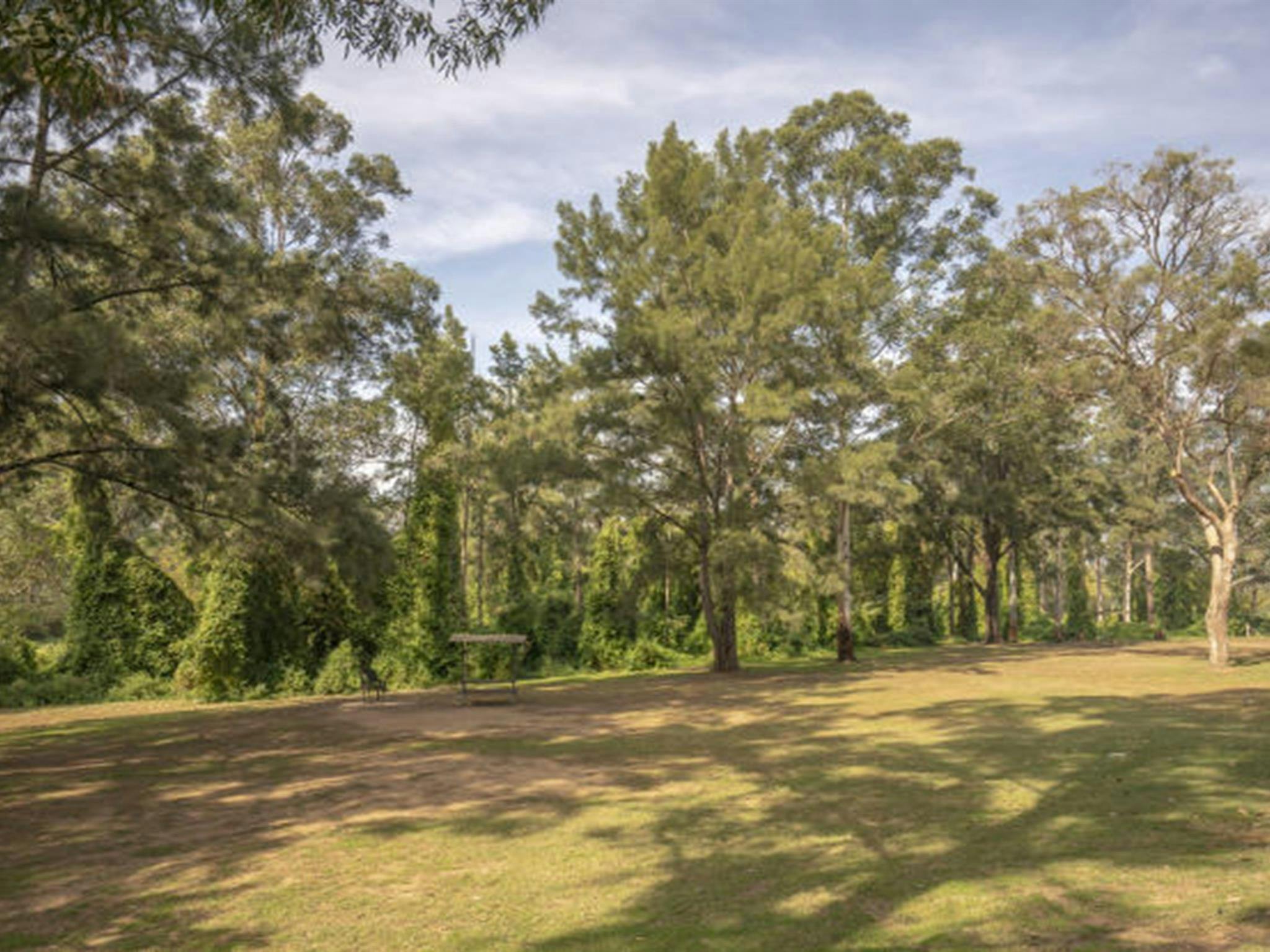 Offene Rasenflächen mit Picknickhütten auf dem Picknickplatz Cattai Farm im Cattai-Nationalpark, auf dem