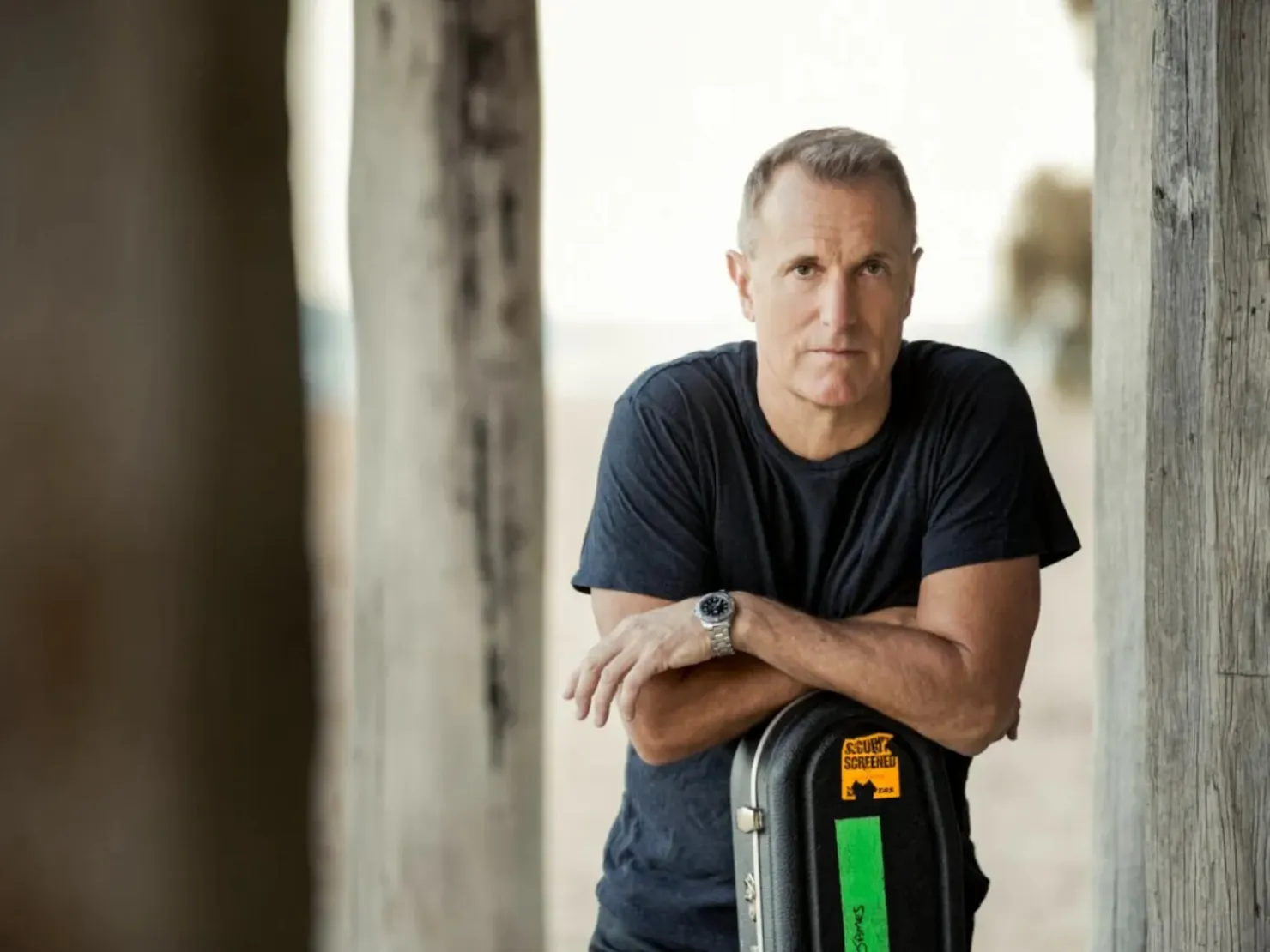 The singer leaning against a guitar case looking into the camera