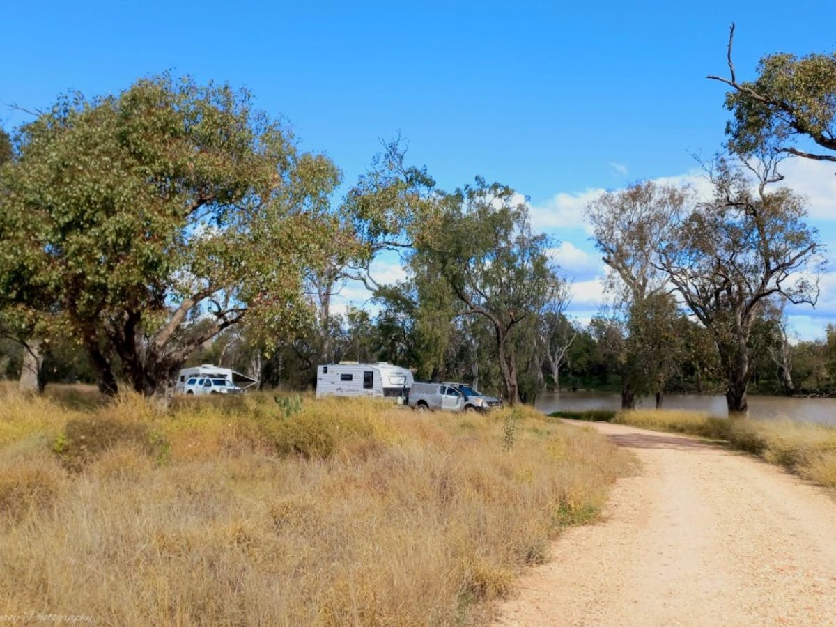 A caravan and car in the distance down a dirt road, camping at Rainbow Reserve A caravan and car in the distance down a dirt road, camping at Rainbow Reserve
