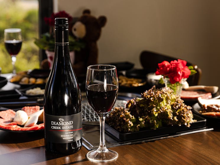 Bottle of 2013 pinot noir australian wine on bbq table with Wagyu Beef and complimentary side dishes