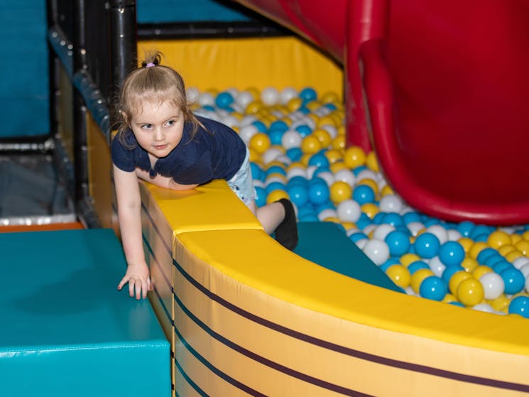 little girl enjoys the ball pit and red slide at Vortex Entertainment