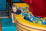 little girl enjoys the ball pit and red slide at Vortex Entertainment