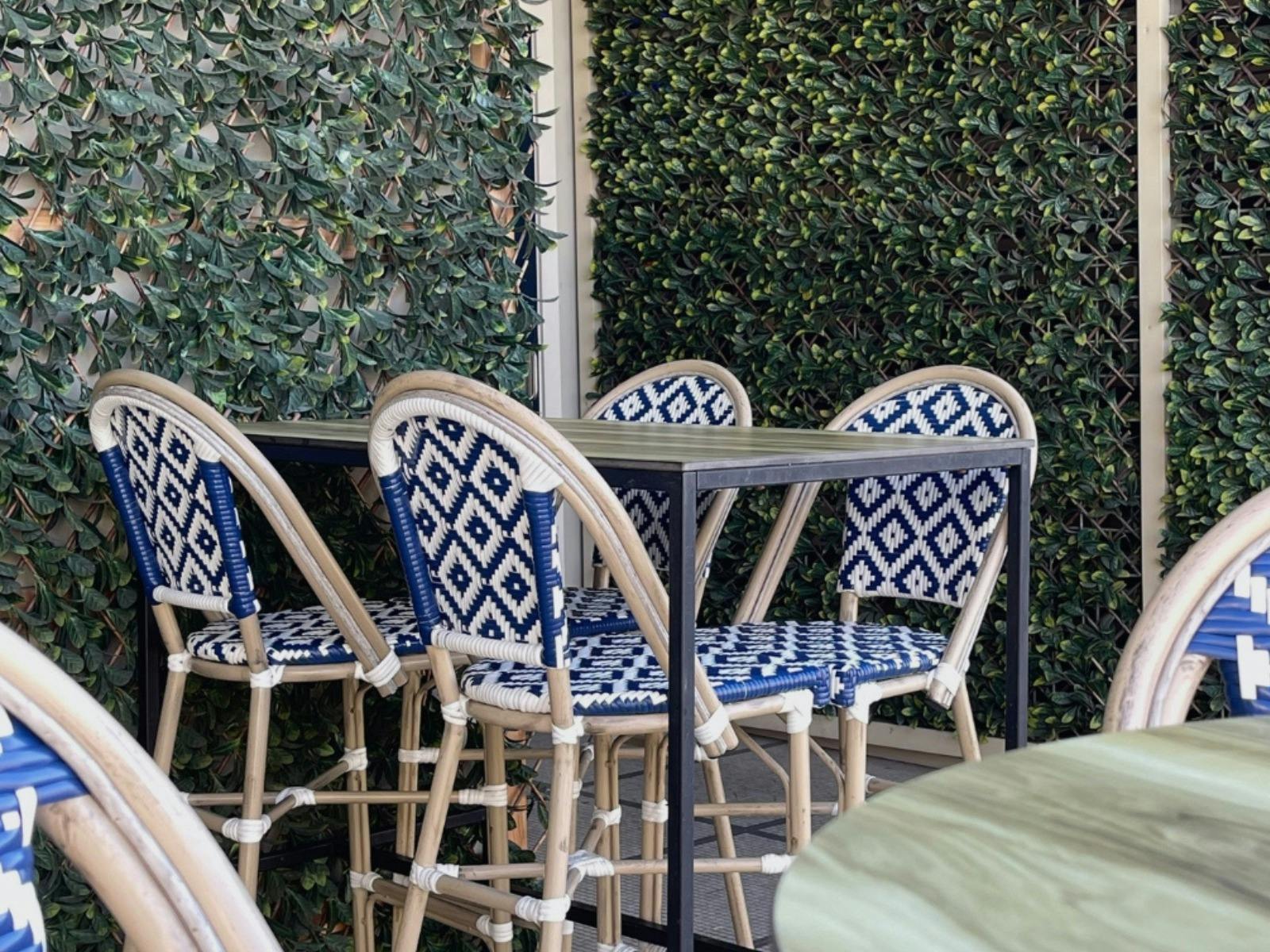 chairs and tables in an out door area at Berkeley Hotel with green hedge behind