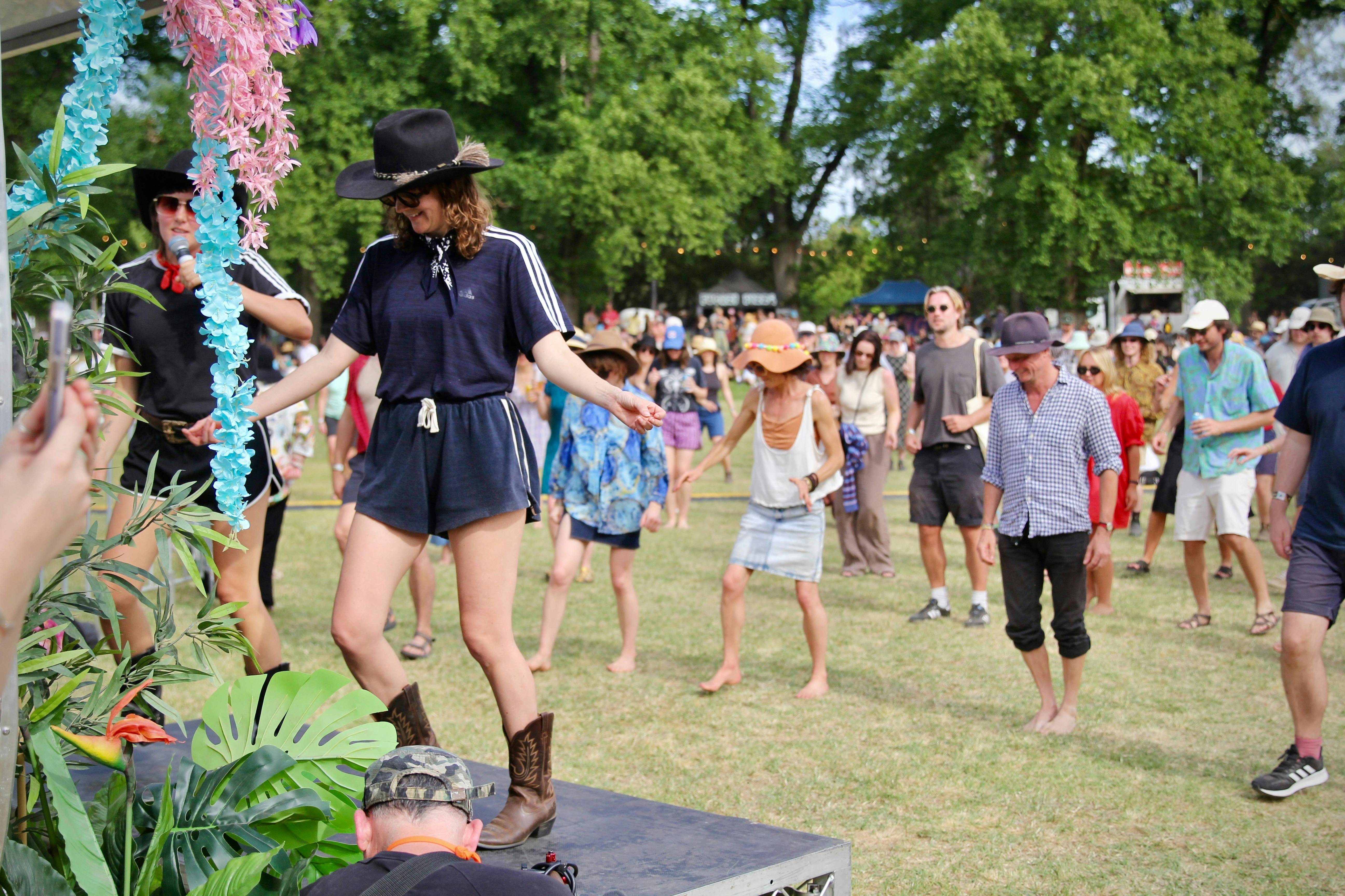 A crowd dancing on grass, following the moves of instructors.