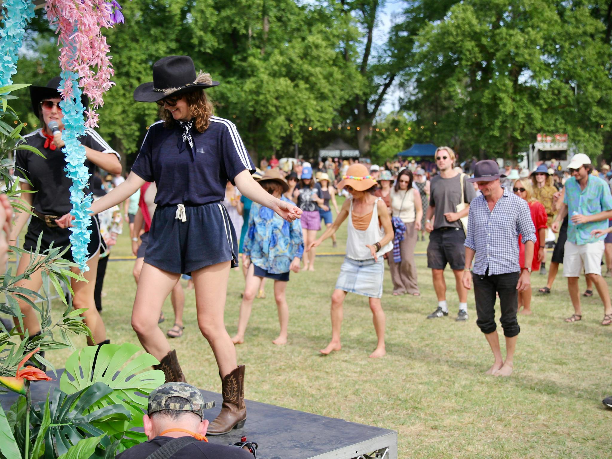 A crowd dancing on grass, following the moves of instructors.