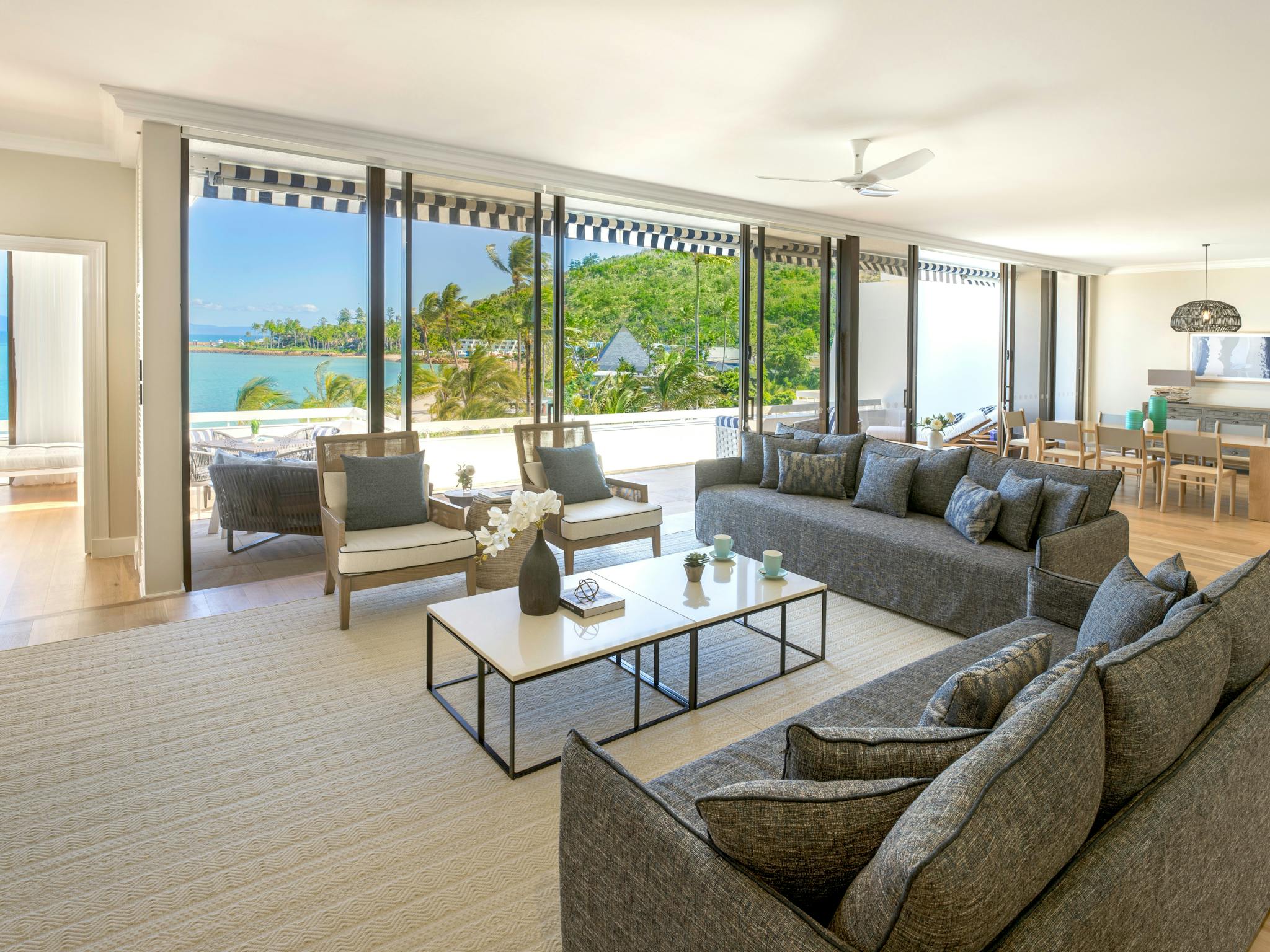 A large, elegant living room with plush seating, floor-to-ceiling windows, and views of the ocean A large, elegant living room with plush seating, floor-to-ceiling windows, and views of the ocean