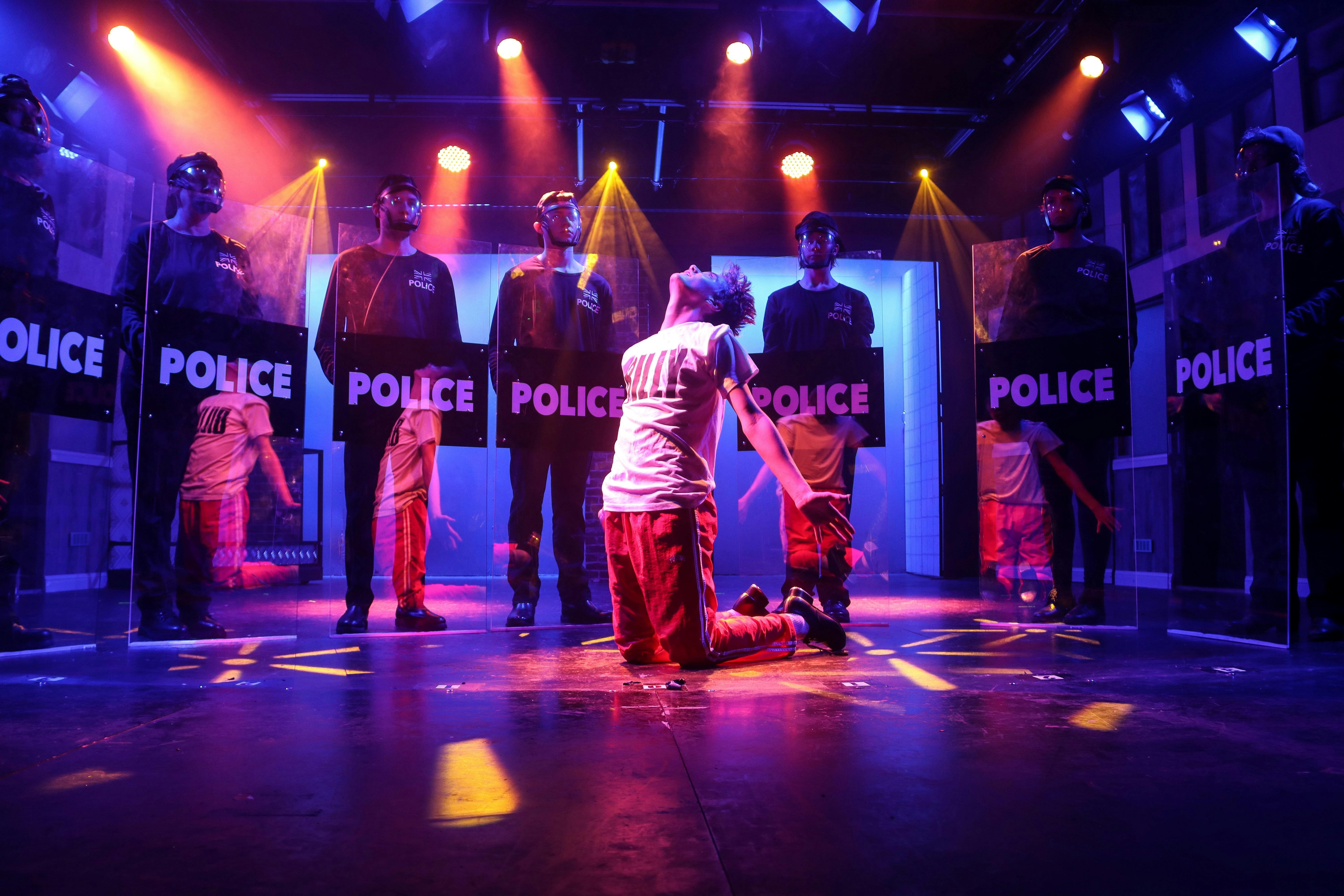 People on stage acting aqs police with a person kneeling in handcuffs