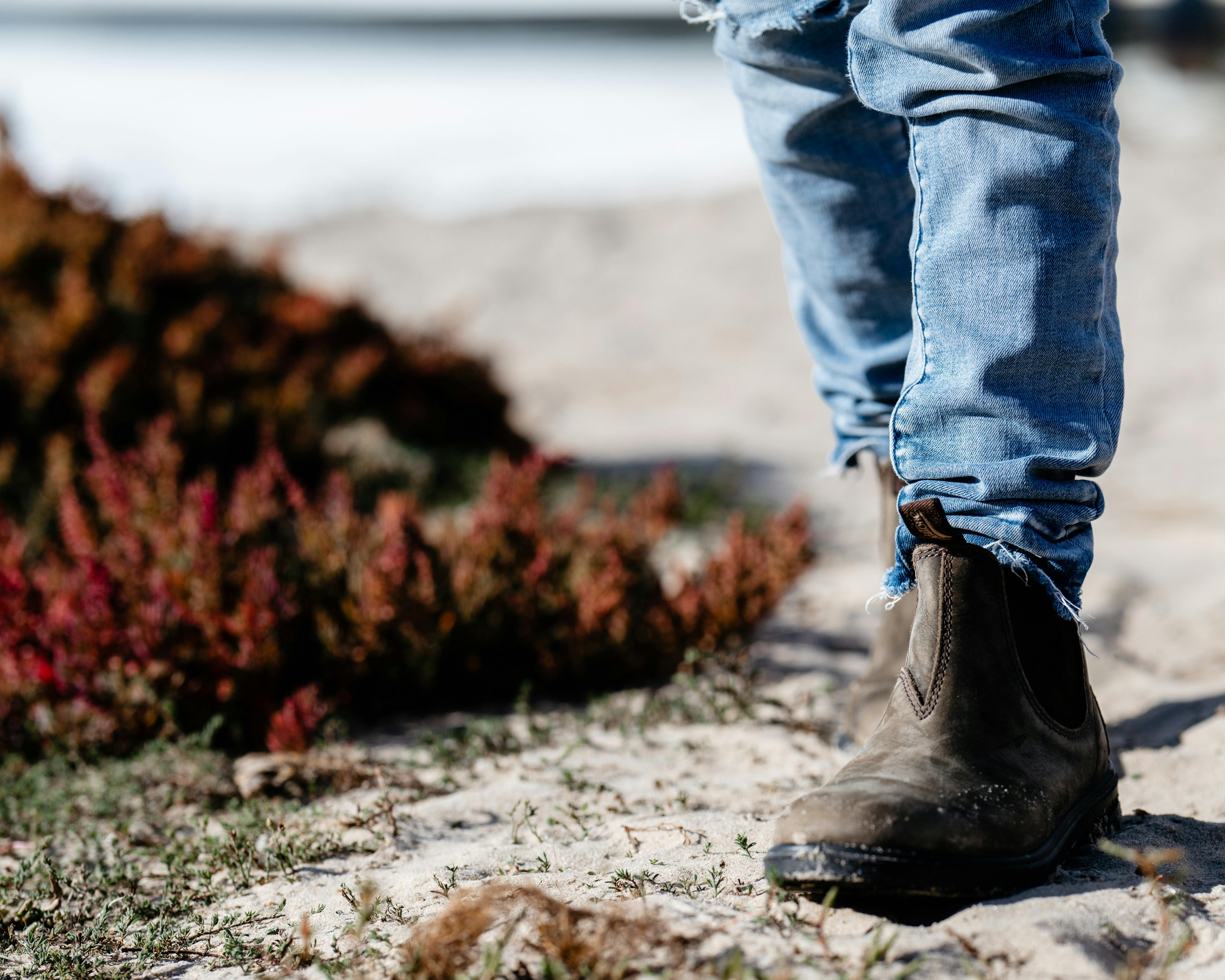 Person walking through the dunes, shot is of their feet in boots and the scrub surrounding them