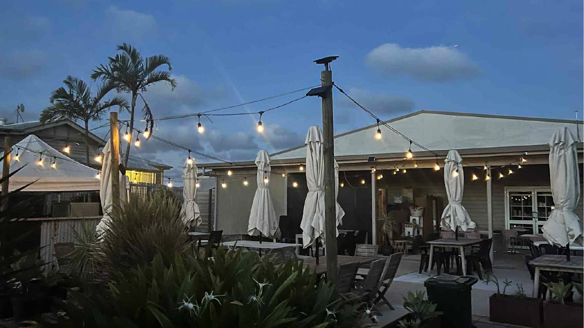 A late evenning image of the outdoor dining area with umbrellas packed away and festoon lighting on