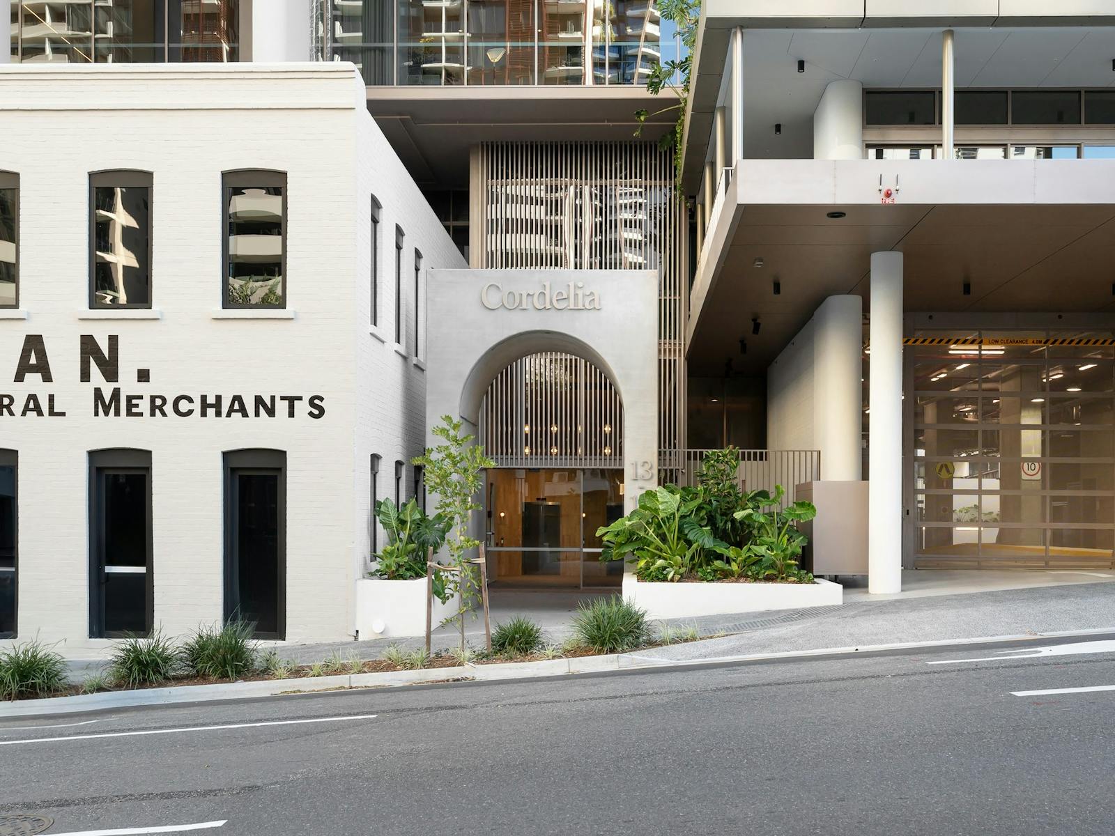 External shot of building with cream coloured facade and archway door. Plants on each side of door. External shot of building with cream coloured facade and archway door. Plants on each side of door.