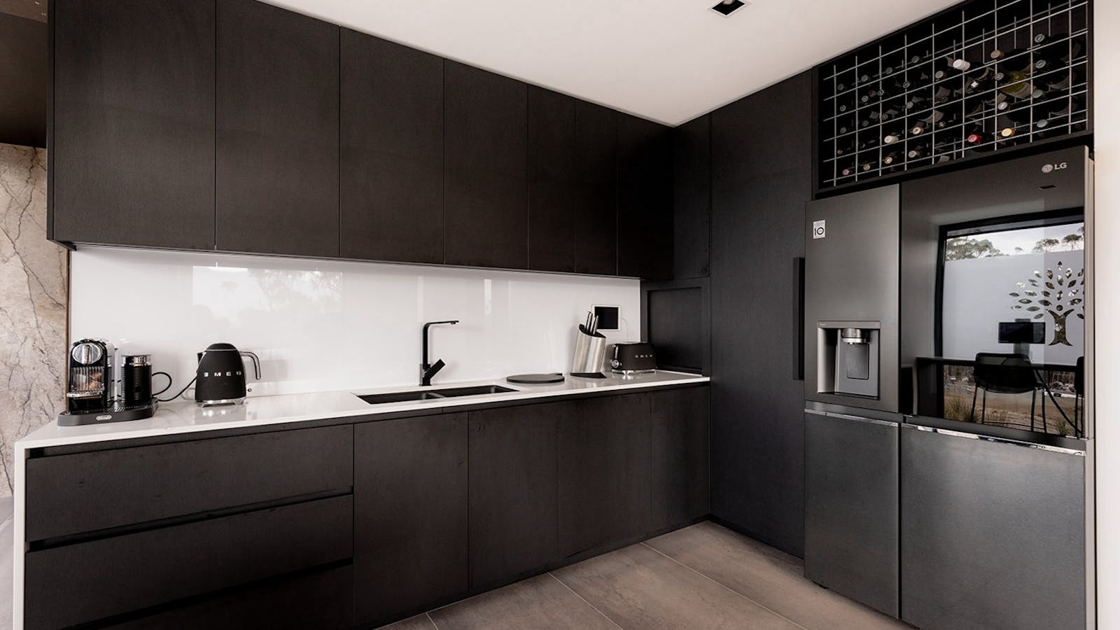 Sleek, fully-equipped black kitchen with modern appliances and marble splashback.