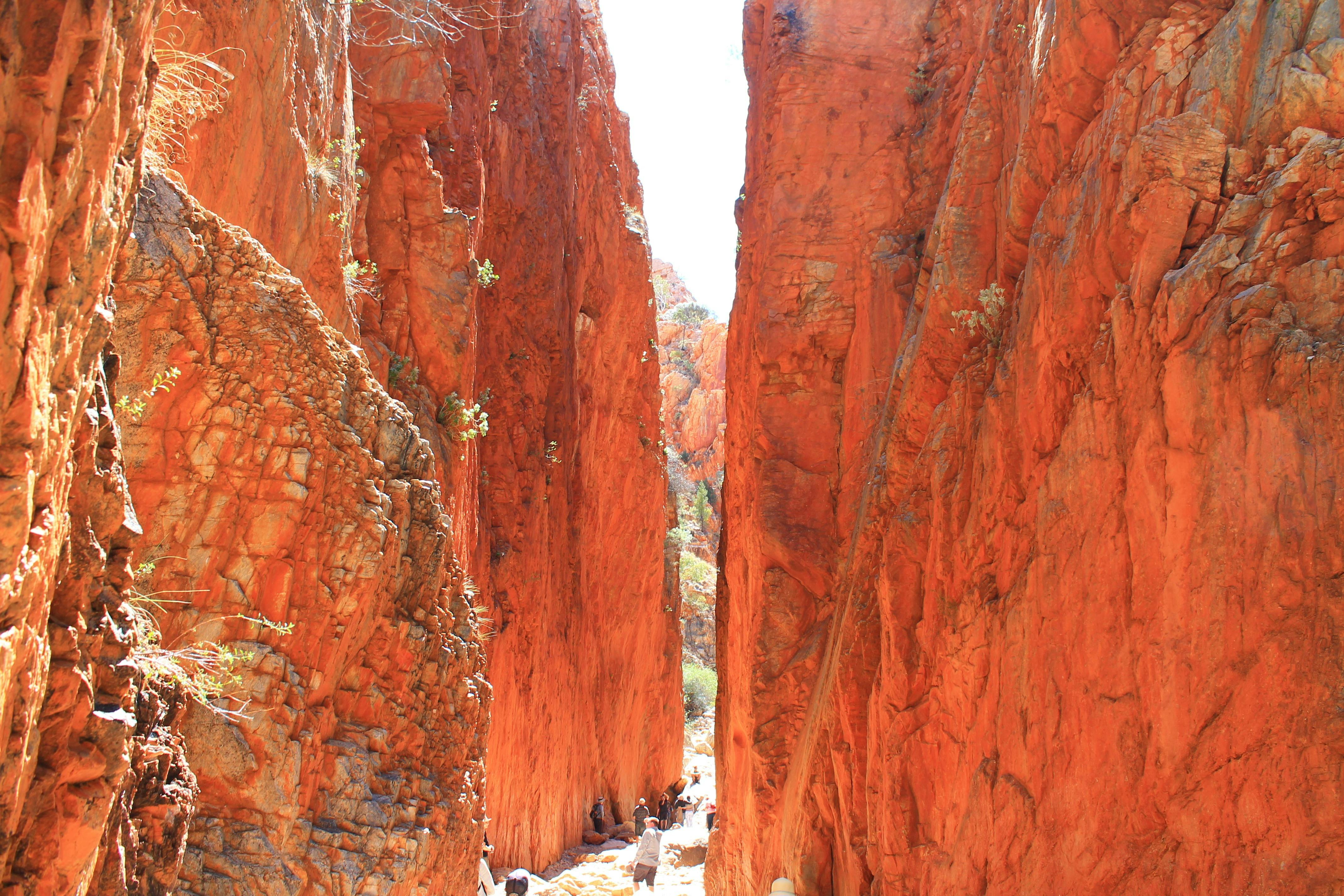 Sheet red cliffs with people walking through the centre gap