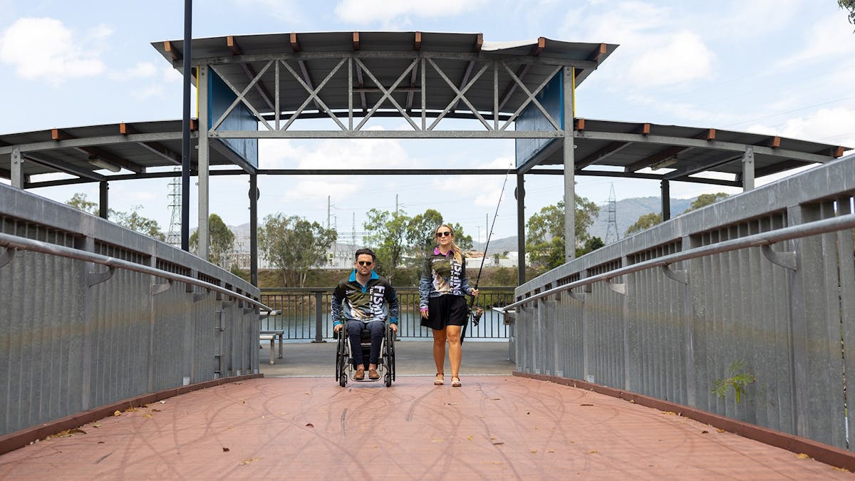 Young couple on a fishing pontoon holding rods.