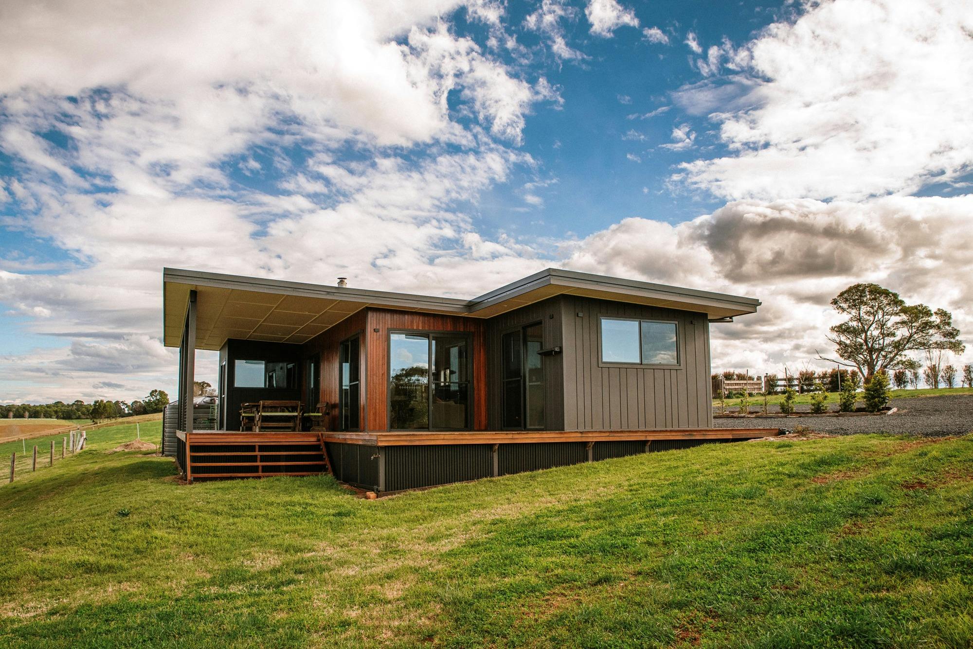 Photo of Dorrigo Rainforest Retreat  cottage with blue sky, clouds and green farmland