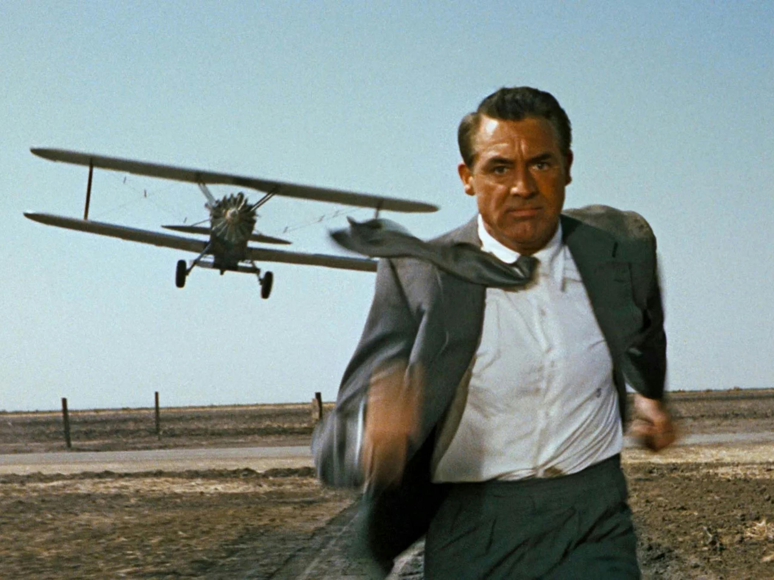 Man in suit and tie running from an airplane