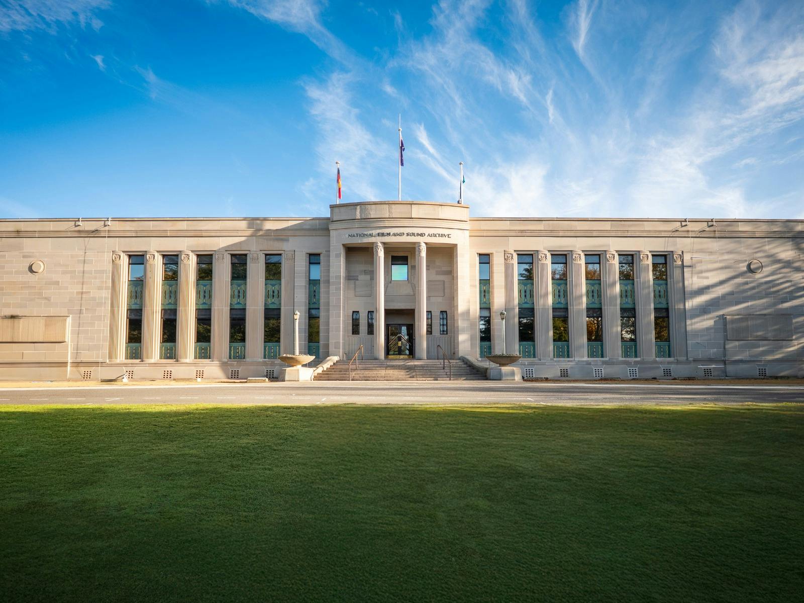 Front of heritage building with green lawn in front and blue sky