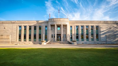 Front of heritage building with green lawn in front and blue sky