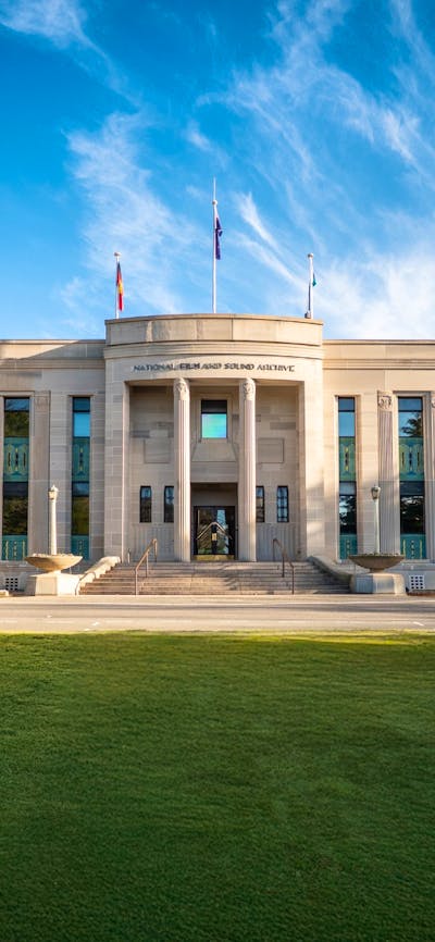 Front of heritage building with green lawn in front and blue sky