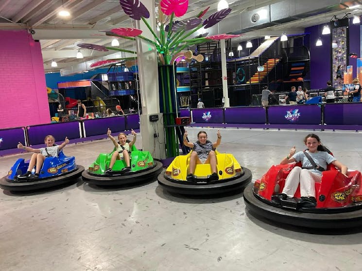 4 teenagers give the thumbs up in brightly coloured bumper cars