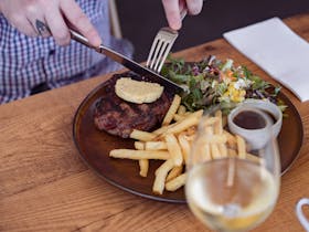 A plated steak with herb butter, crispy fries, and salad served at Bushmanu2019s Arms Hotel.