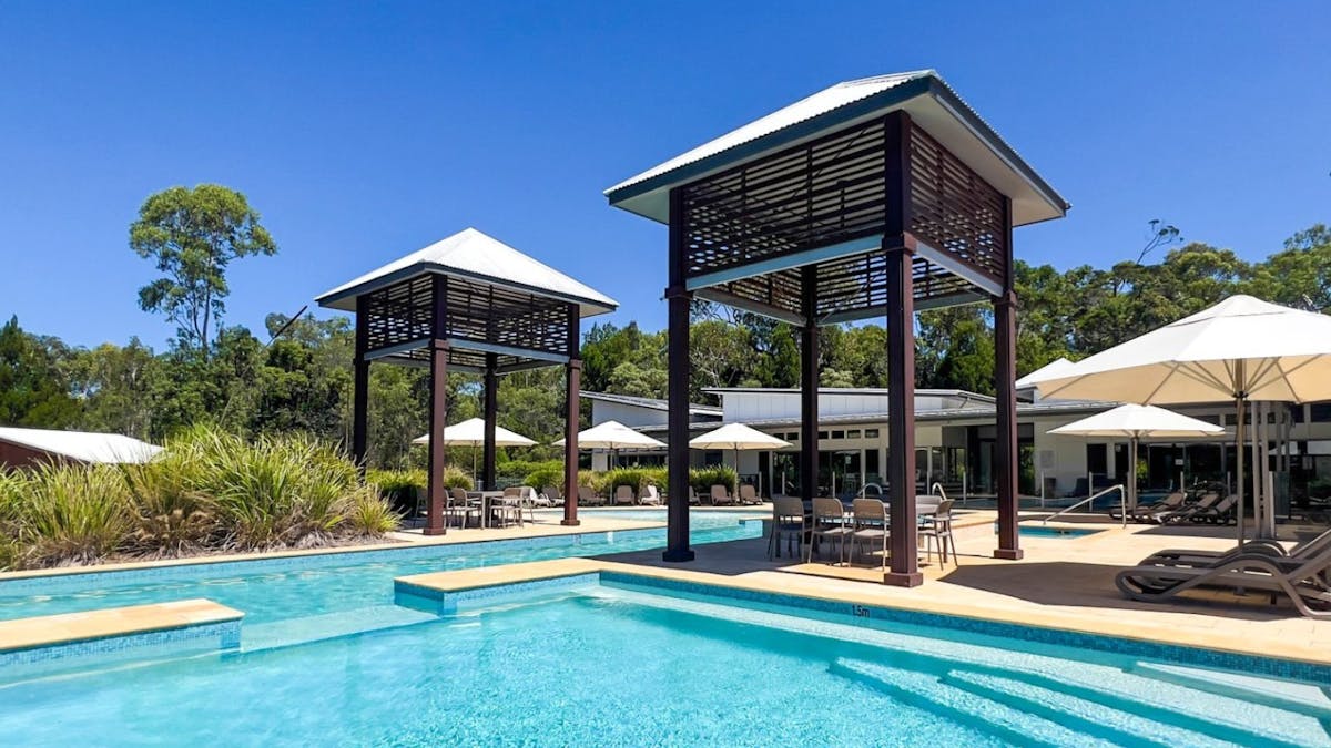 Large blue pool area with a lap pool, spa, and spacious undercover seating and BBQ areas.