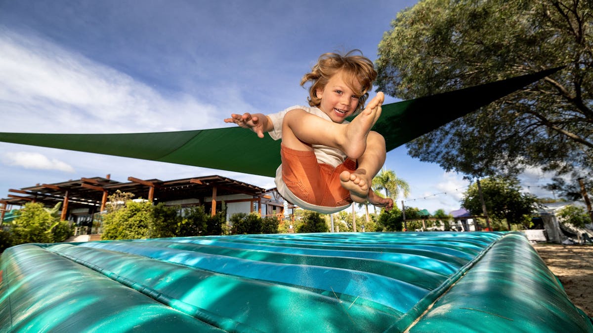 child on blue and green jump mat